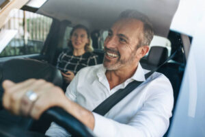 Taxi driver talking to a female passenger sitting in backseat. Businesswoman using taxi ride to go to work.